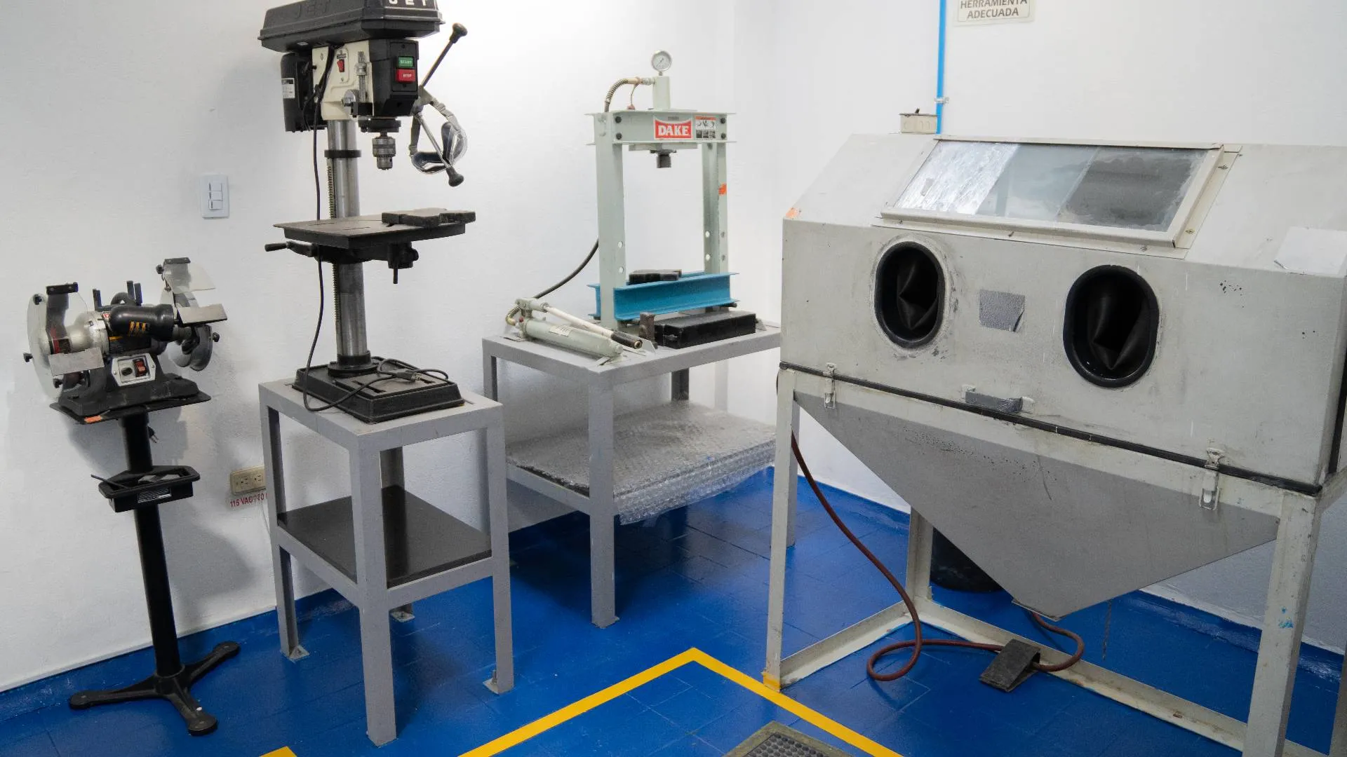 A room featuring a machine on one side and a table positioned in the center, with neutral-colored walls.